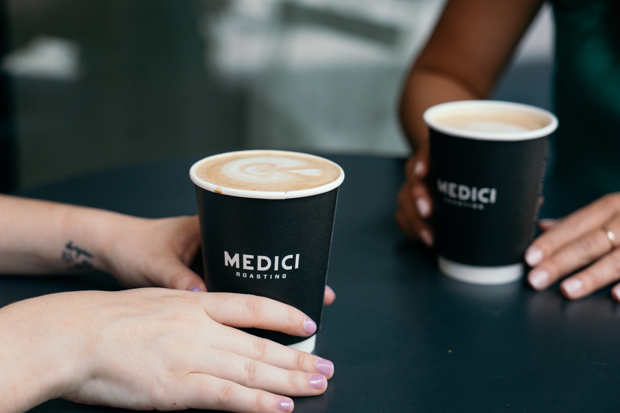 Two women holding mocha cups from Medici