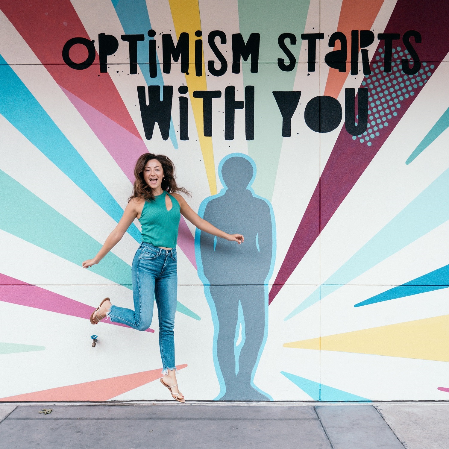 Woman jumping in front of colorful outdoor mural
